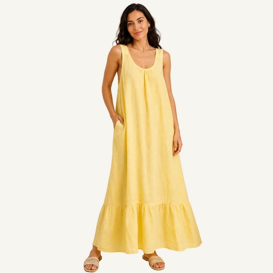 Woman wearing a yellow dress standing next to a plant on a plain background