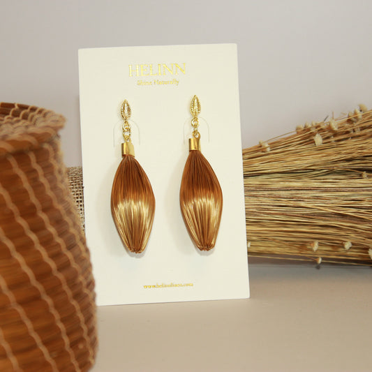 Handmade HELINN Folha Dourada Golden Grass leaf earrings displayed on natural artisan background.