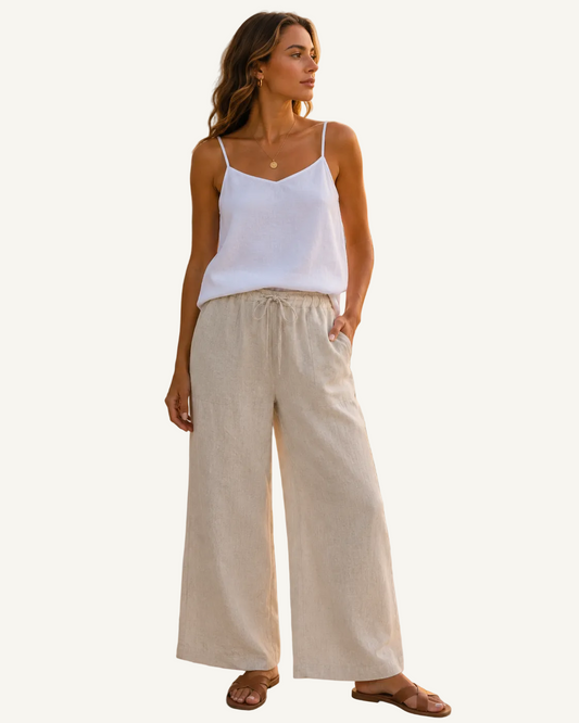 Woman wearing the Helinn Biscayne Linen Top in Ocean White featuring adjustable straps and breathable European flax linen styled in a tropical coastal setting.