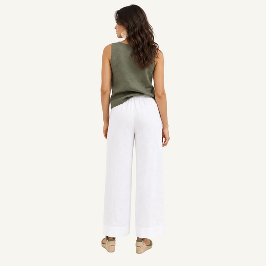 A woman is shown from the back wearing a sleeveless olive green top and white wide-leg pants, standing against a plain white studio background.