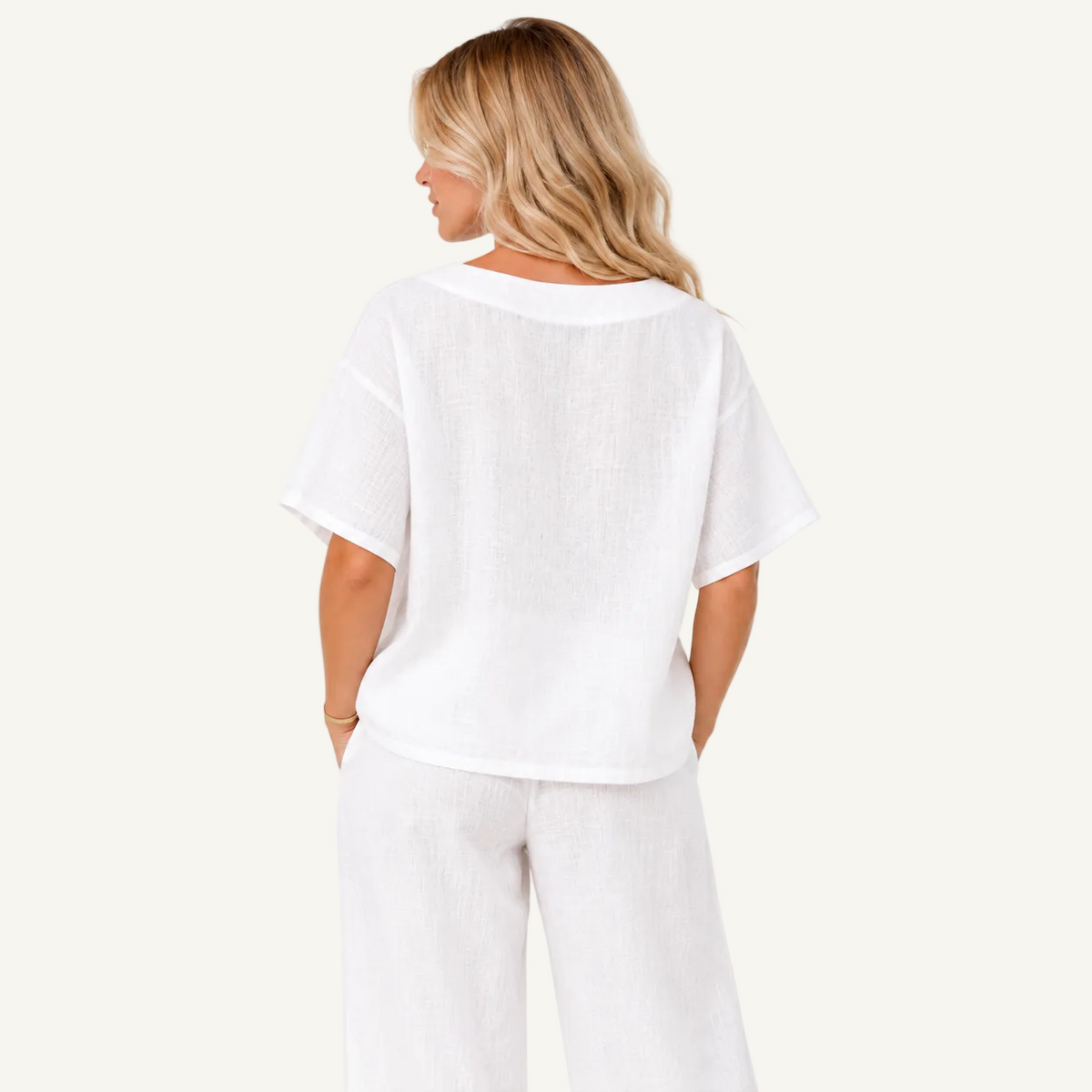 A woman shown from the back wearing a white short-sleeve linen top and matching white pants against a plain white background.