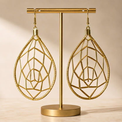 Gold geometric earrings on a matching stand against a beige background