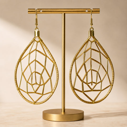 Gold geometric earrings on a matching stand against a beige background