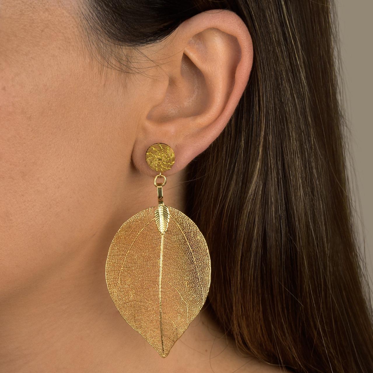 Woman wearing Aura Leaf Statement Earrings handcrafted with Brazilian Golden Grass and delicate gold botanical leaf pendant.