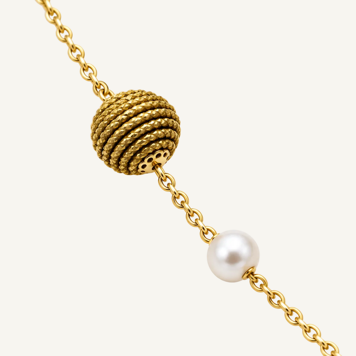 A gold chain bracelet featuring a textured spherical bead and a single white pearl bead, shown on a clean white background.