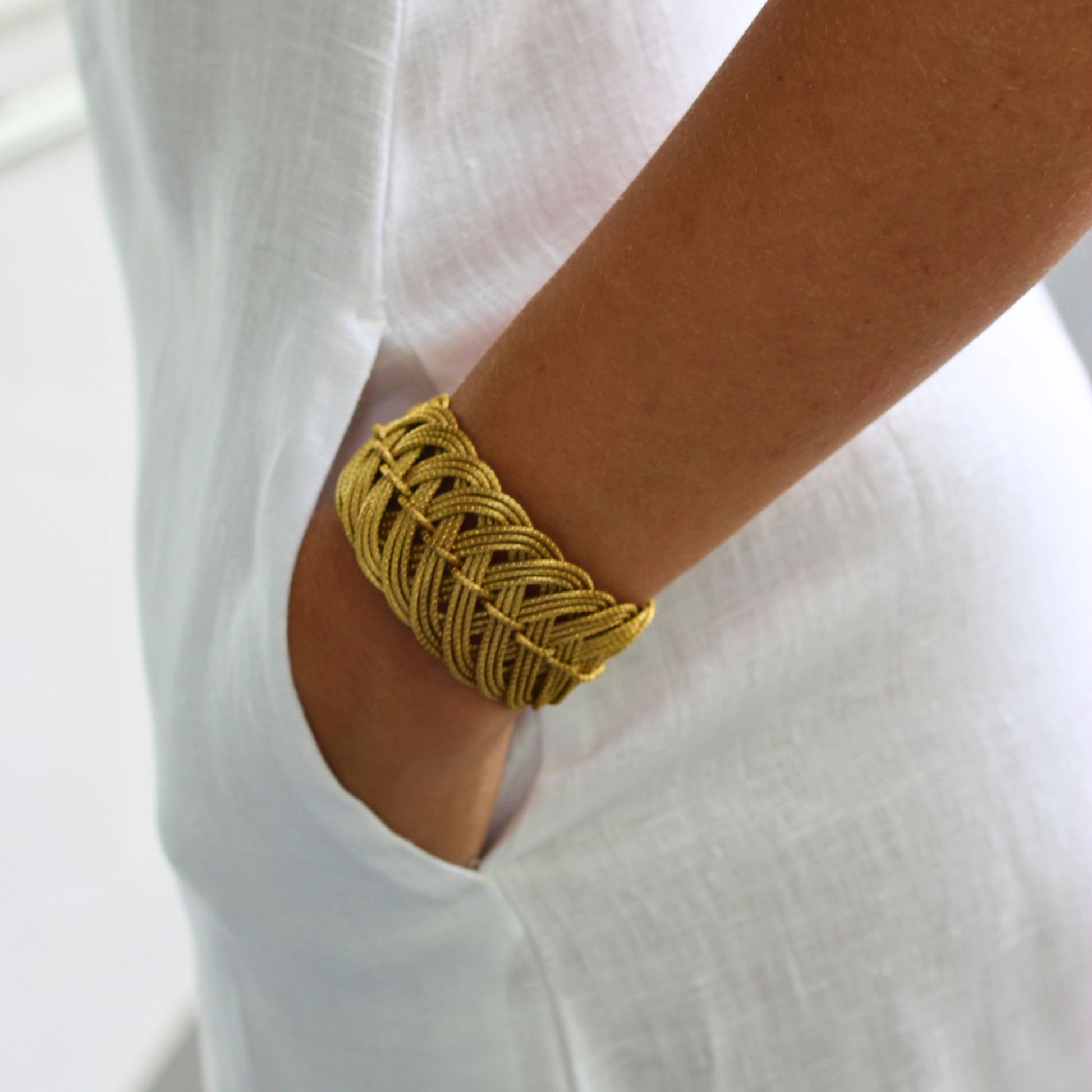 Gold bracelet on a person's wrist with a white background