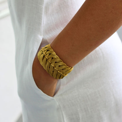 Gold bracelet on a person's wrist with a white background