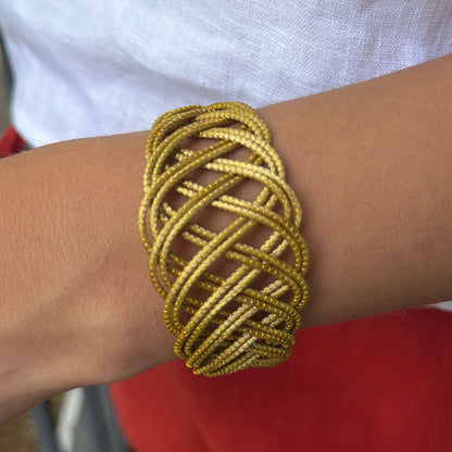 Handwoven golden grass cuff bracelet inspired by flowing sand dunes and natural movement.