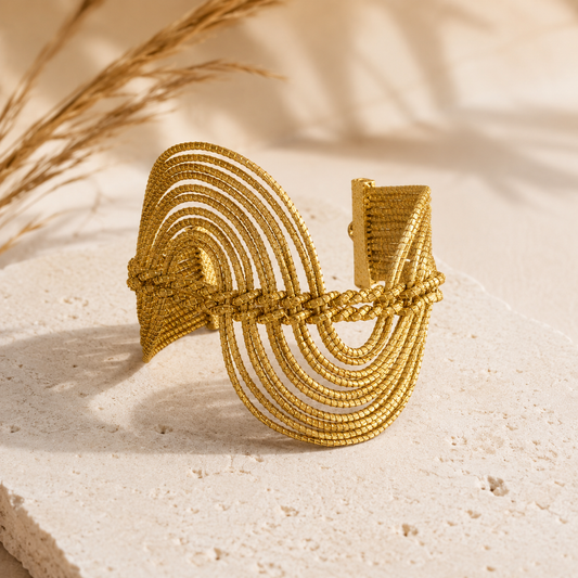 Woman wearing the HELINN Essência do Cerrado Golden Grass cuff bracelet styled with a black linen dress in warm natural light, showcasing handcrafted Brazilian artisan jewelry.