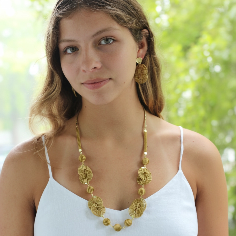Woman wearing a gold necklace and earrings outdoors