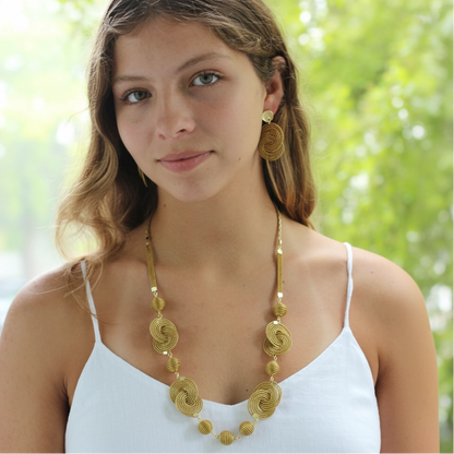 Woman wearing a gold necklace and earrings outdoors