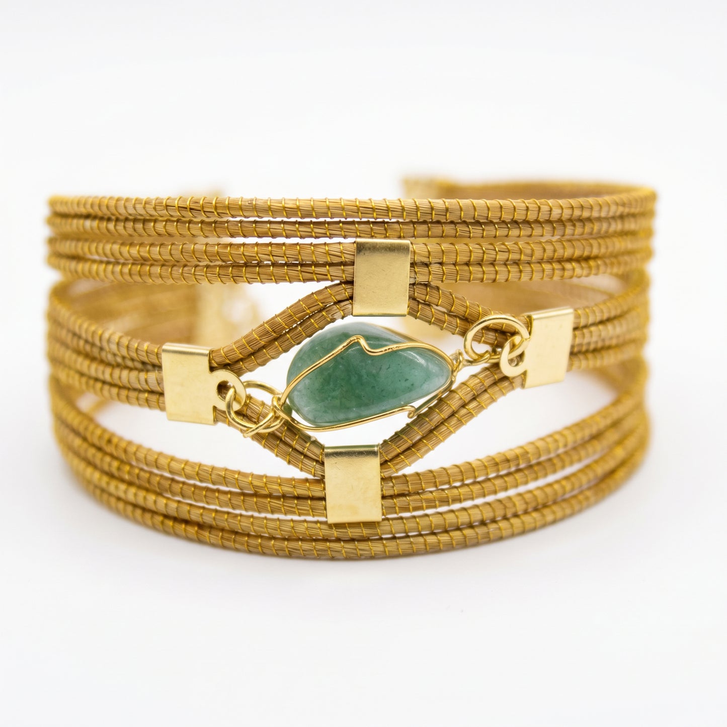 Gold bracelet with a green stone on a white background