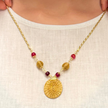 Woman wearing a gold necklace with red beads on a white background