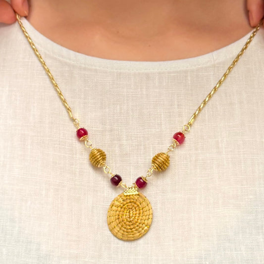 Woman wearing a gold necklace with red beads on a white background