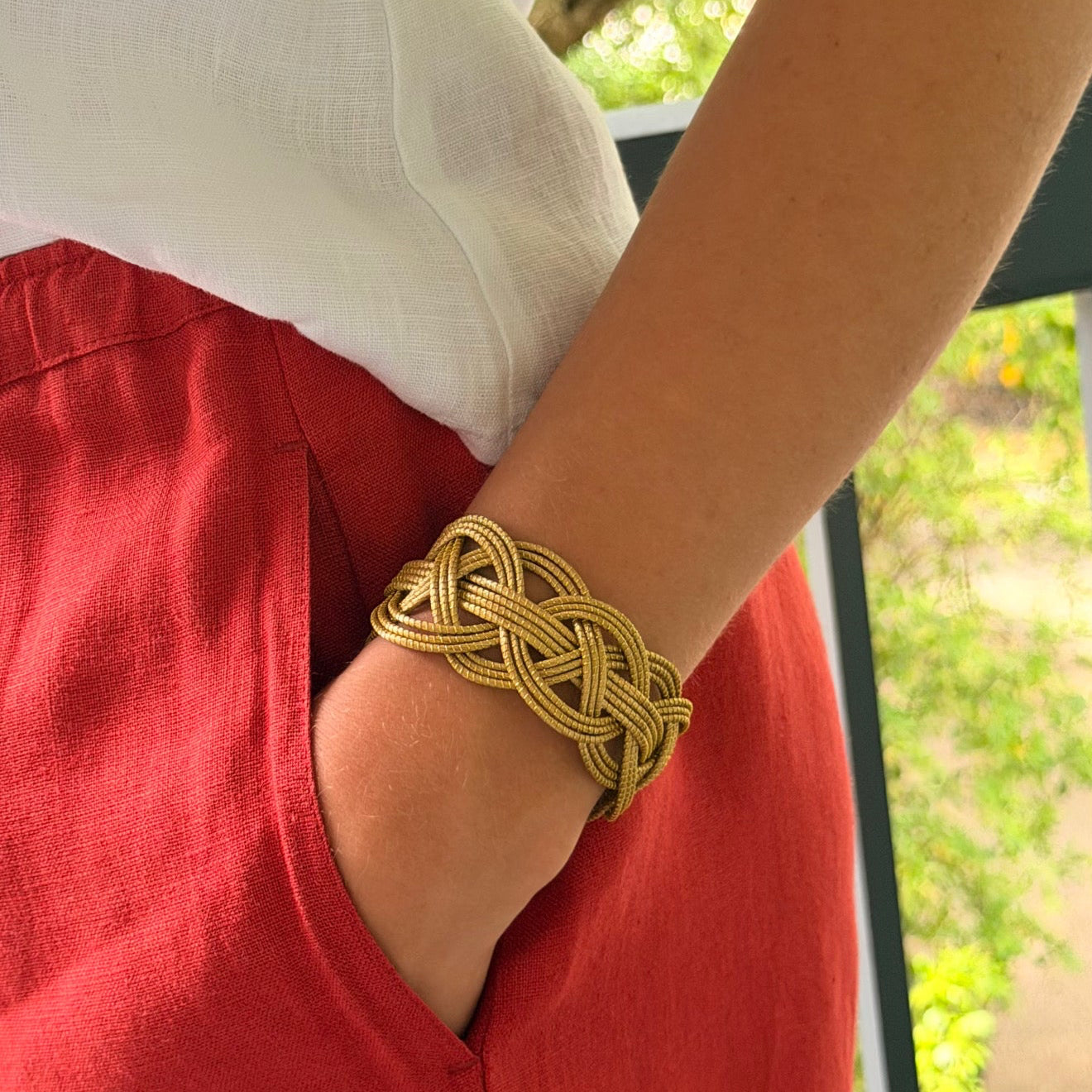 Horizonte Serena braided golden grass cuff bracelet styled with white linen top and red linen pants by HELINN
