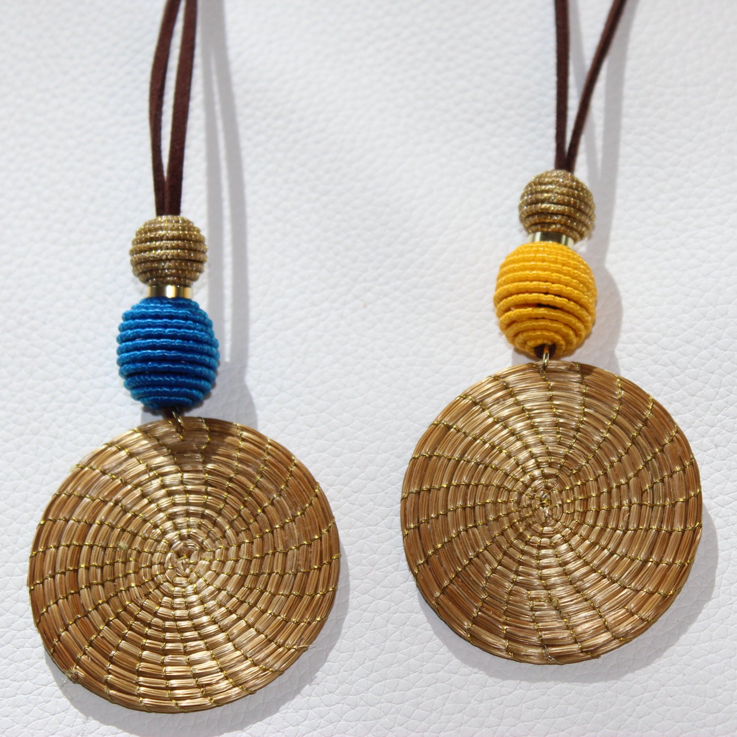 Woven disc pendants with colorful beads on a white background