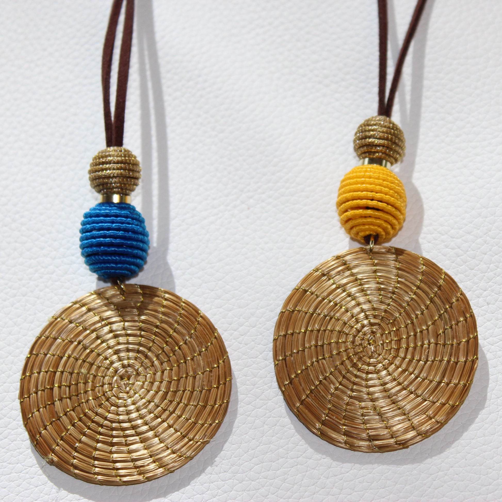 Woven disc pendants with colorful beads on a white background