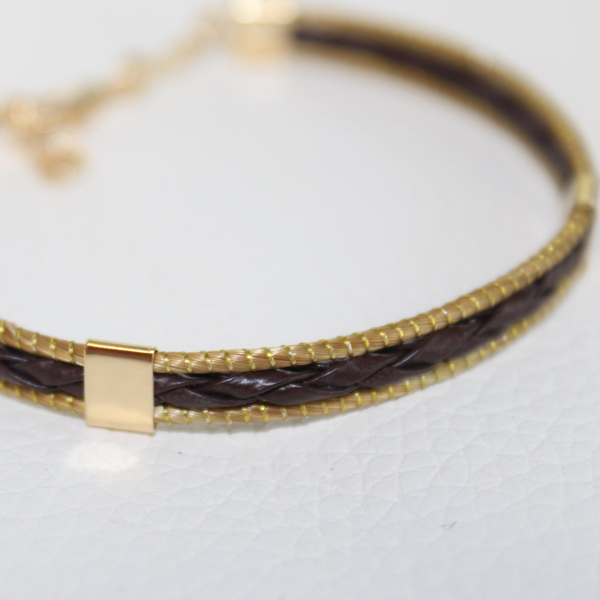 Close-up of the braided leather and polished 18K gold-plated detailing on the HELINN Aura Slim Leather Bracelet.