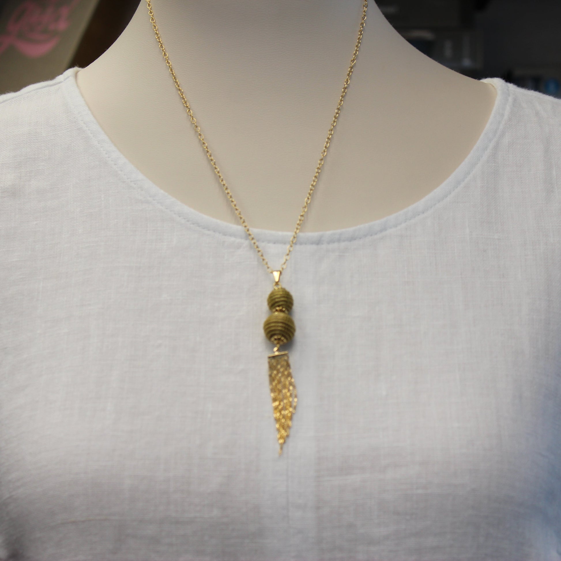 Handcrafted from Brazilian Golden Grass with premium 18K gold-plated details, the Aura Long Gold Drop Necklace features elegant woven spheres and a flowing tassel for timeless sophistication.