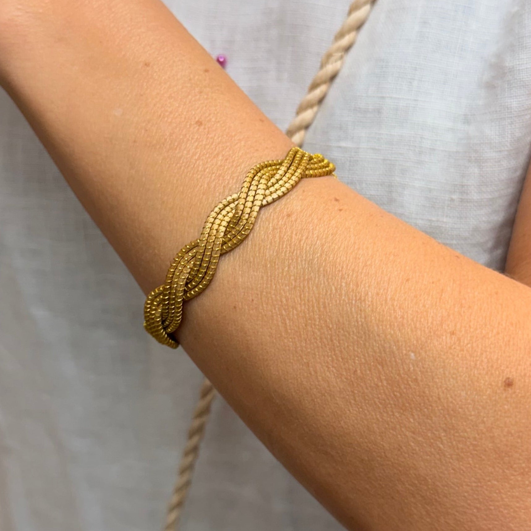 Gold bracelet on a person's wrist with a blurred background