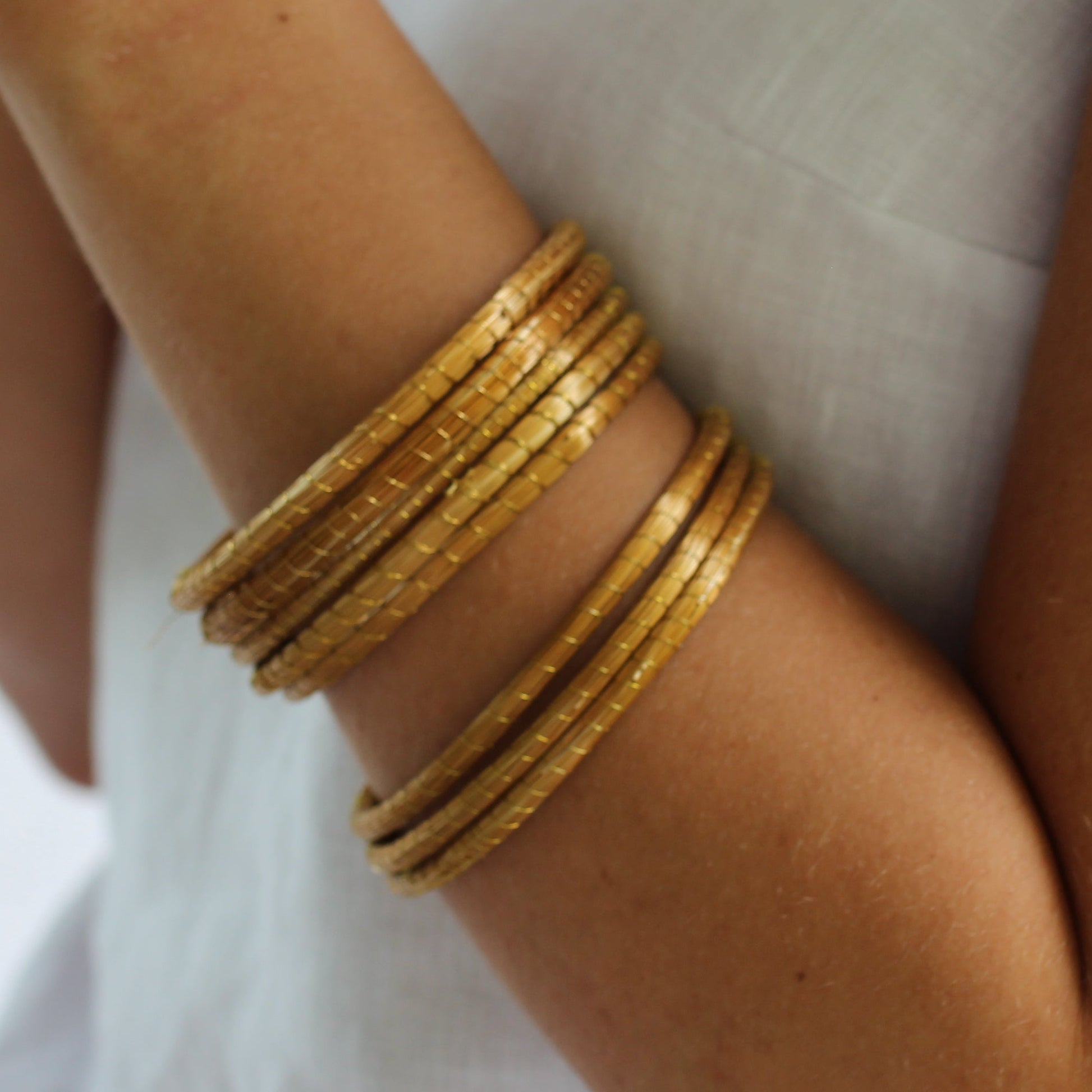 Person wearing gold bangles on a blurred background
