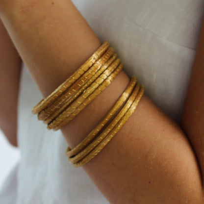 Person wearing gold bangles on a blurred background