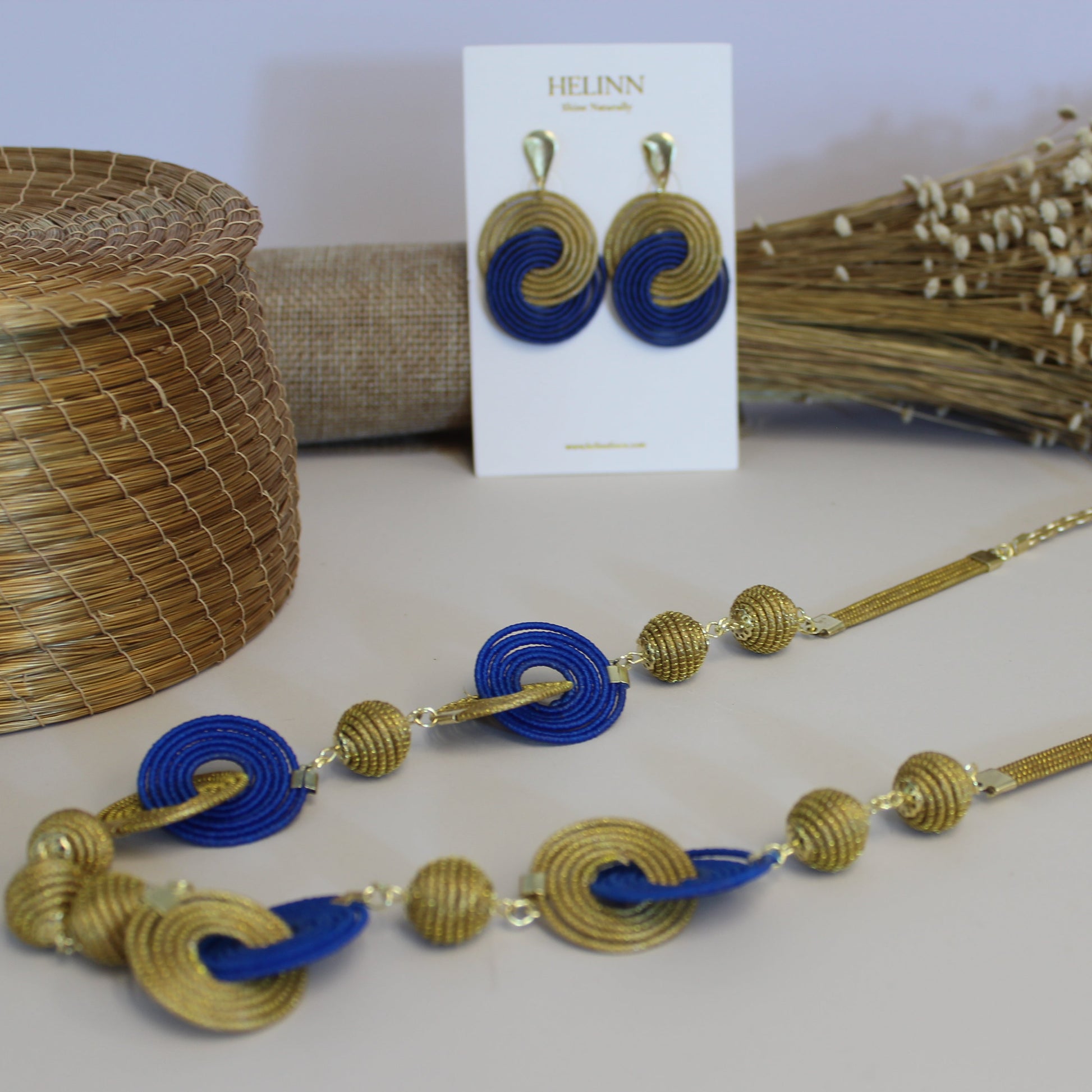 Gold and blue necklace on a white surface with a card in the background