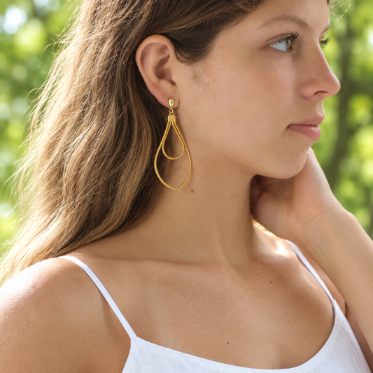 Woman wearing Brisa Dourada golden natural fiber earrings by HELINN