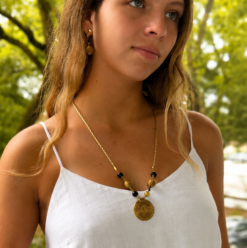 Woman wearing a white dress with a necklace in an outdoor setting