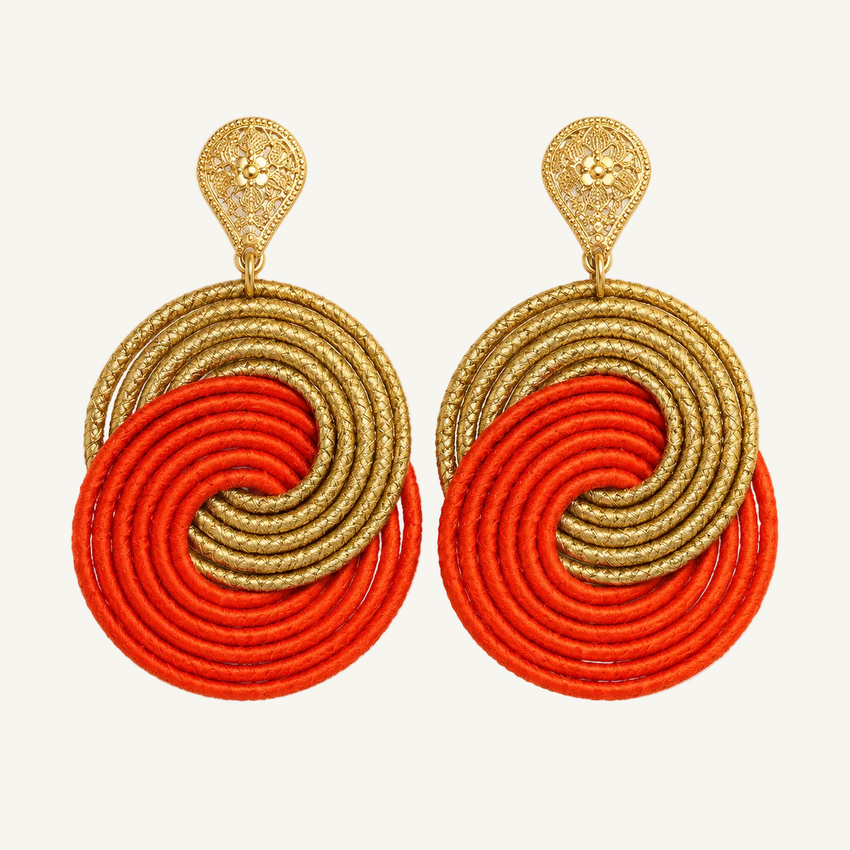 A pair of statement dangle earrings featuring textured gold metal filigree studs and large circular disc elements in alternating metallic gold and bright orange-red cord, set against a plain white background.